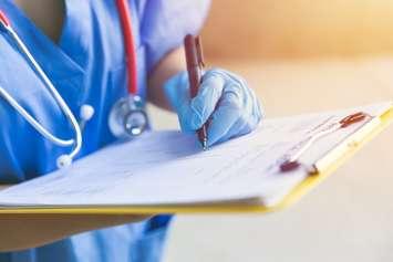 Nurse writing on clipboard