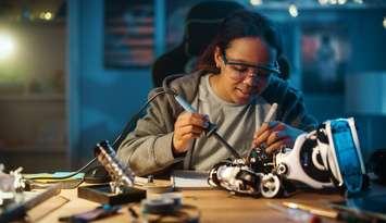 A young women soldering wires and circuit boards. (Image from gorodenkoff / iStock / Getty Images Plus / via Getty Images)