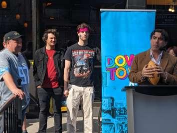 Windsor Ward 3 Councillor Renaldo Agostino, right, is joined by DWBIA Chair Chris MacLeod, far left, and Robbie Cervi from the band Huttch, in red shirt, in announcing the NFL Draft block party outside Lefty's On the O in downtown Windsor, April 18, 2024. Photo by Mark Brown/WindsorNewsToday.ca.