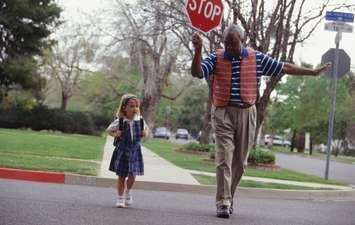 Girl crossing the street with crossing guard (photo courtesy: Steve Mason/ Getty Images)
