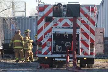 Tecumseh firefighters discuss a brush fire behind a business on Ure St on  March 17, 2018. Photo by Mark Brown/Blackburn News.