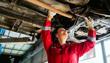 A woman working on a vehicle (Photo by: iStock / Getty Images Plus/ 	Artit_Wongpradu)