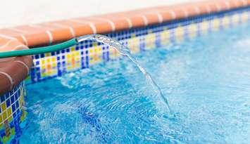 Water hose filling up swimming pool. (Vitalina Nakonechna / iStock via Getty Images)