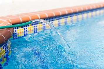 Water hose filling up swimming pool. (Vitalina Nakonechna / iStock via Getty Images)