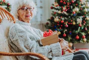 Elderly lady holding Christmas gift (Image by YakobchukOlena / iStock / Getty Images Plus via Getty Images)