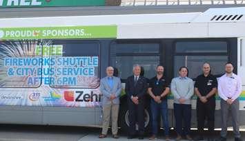 Transit Windsor Executive Director Tyson Cragg, left, Windsor Ward 7 Councillor Angelo Marignani, and representatives from Zehrs show off a bus with decals announcing the annual Ford Fireworks shuttle, May 21, 2024. Photo by Mark Brown/WindsorNewsToday.ca.