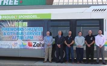 Transit Windsor Executive Director Tyson Cragg, left, Windsor Ward 7 Councillor Angelo Marignani, and representatives from Zehrs show off a bus with decals announcing the annual Ford Fireworks shuttle, May 21, 2024. Photo by Mark Brown/WindsorNewsToday.ca.