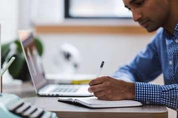 Man working on laptop and writing work