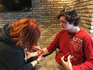 The Painted Cat's Cat Cabajar places a fake wound on Great Lakes Secondary School Grade 11 drama student Kade Clarke. Clarke was participating in a mass casualty simulation at Progressive Auto Sales Arena. April 12, 2018 (Photo by Melanie Irwin)