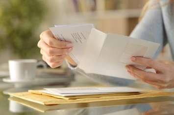 Woman opening a letter (Image from Pheelings Media / iStock / Getty Images Plus via Getty Images)