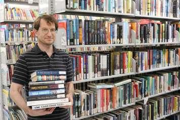 Library Technician holds items available for purchase at the upcoming used book sale. July 2022. (Photo courtesy of Lambton County Library) 
