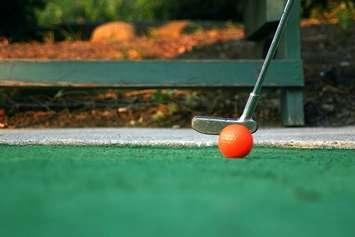 A person putting at a mini-golf course. File photo courtesy of © Can Stock Photo / JamieWilson. 