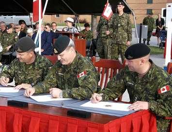 Signing copies of the Change of Command protocol are Lieutenant Colonel Bryan Bedard (left) and Lieutenant Colonel Christian Lillington (at right).   Brigadier General Lowell Thomas (centre) oversees the signing over of command. 
Photo by James Armstrong  