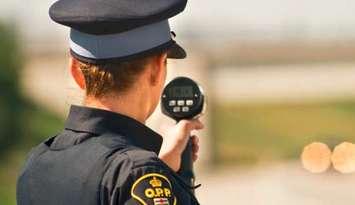 An Ontario Provincial Police officer with a radar speed gun. (Photo by OPP)