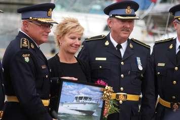 Former OPP Commissioner Chris Lewis (left) stands with his wife and other officers holding a picture of the new OPP marine vessel carrying his name at a ceremony held at the Leamington Marina on June 23, 2016. (Photo by Ricardo Veneza)