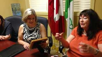Cheri Hernandez talks about her struggles with the long-term care system in Ontario as NDP leader Andrea Horwath admires a photo of Hernandez's mother in Windsor on July 6, 2017. Photo by Mark Brown/Blackburn News