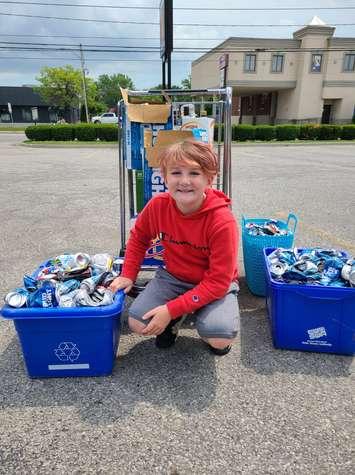 Haze Jaxon Hill is seen with bins of empty bottles, collected to raise money for dogs with cleft palettes. Photo by Susan Hill/Facebook.