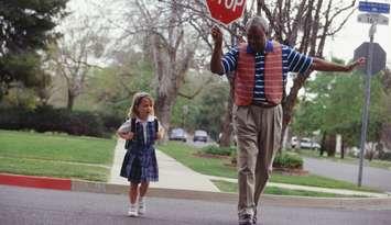 Girl crossing the street with crossing guard (photo courtesy: Steve Mason/ Getty Images)