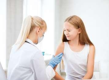 A healthcare professional giving a vaccine to a girl. © Can Stock Photo / dolgachov