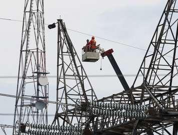 Two Hydro One employees work at the top of a transmission tower to pull new shield wire across the St. Clair River. (Photo submitted by Hydro One)