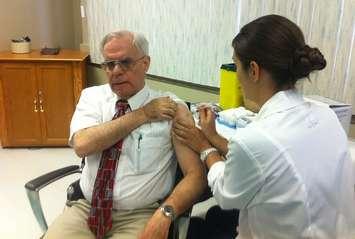 Retired Medical Officer of Health Dr. Allen Heimann receiving his 2013 flu shot. 