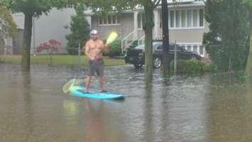 A man uses a paddle board to get around Glendale Ave. in east Windsor following widespread flooding, August 29, 2017. (Photo courtesy of Mike Hello)