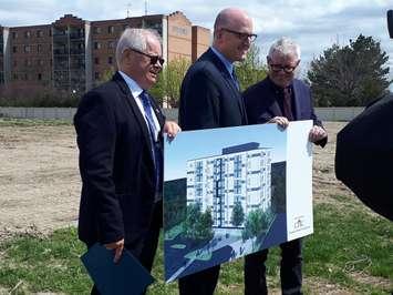 Jim Steele, CEO of the Windsor-Essex Community Housing Corporation, left; Windsor Mayor Drew Dilkens, and MP Adam Vaughan show off a drawing of a housing block set to be built on Meadowbrook Lane, April 23, 2019. Photo by Mark Brown/Blackburn News.