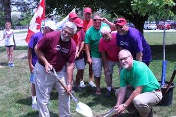 Essex County Warden Thomas Bain (left), Tecumseh deputy mayor Joe Bachetti (right, in purple shirt), and Essex County CAO Brian Gregg (far right) join other county council members in burying the Canada150 time capsule on July 21, 2017 (Photo by Mark Brown/Blackburn News)