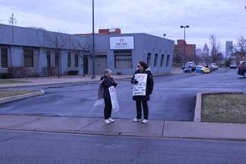 A couple of the 10 striking Canadian Hearing Society workers stand outside of the office on Giles Blvd. in Windsor, joining in the Province-wide action, March 6, 2017. (Photo by Mike Vlasveld)