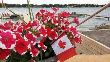 A Canadian flag is seen among red and white flowers (Photo courtesy of Arlette Payne/Facebook)