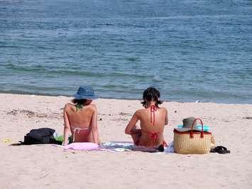 Two women sitting on the beach. Photo courtesy of © Can Stock Photo / Razvanjp.