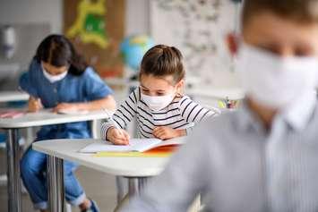 Children wearing face masks in school. (File photo courtesy of © Can Stock Photo / halfpoint)