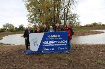Ed Sleiman, Tracey Ramsey, Ian McRobbie, Claire Wales,  Taras Natyshak and Annette Zahaluk unveil the sign for the Holiday Beach Demonstration Wetland. (Photo courtesy ERCA)