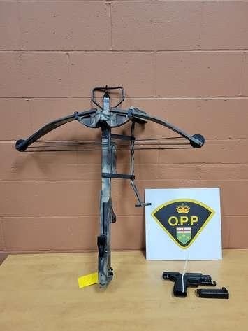 A crossbow and firearm seized in a raid on January 31, 2023, are displayed. Photo courtesy Ontario Provincial Police.